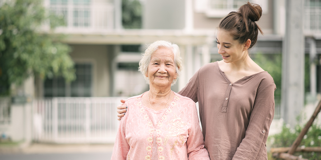 Eine junge Frau hält eine Seniorin in Arm. Eine junge Frau hält eine Seniorin in Arm.